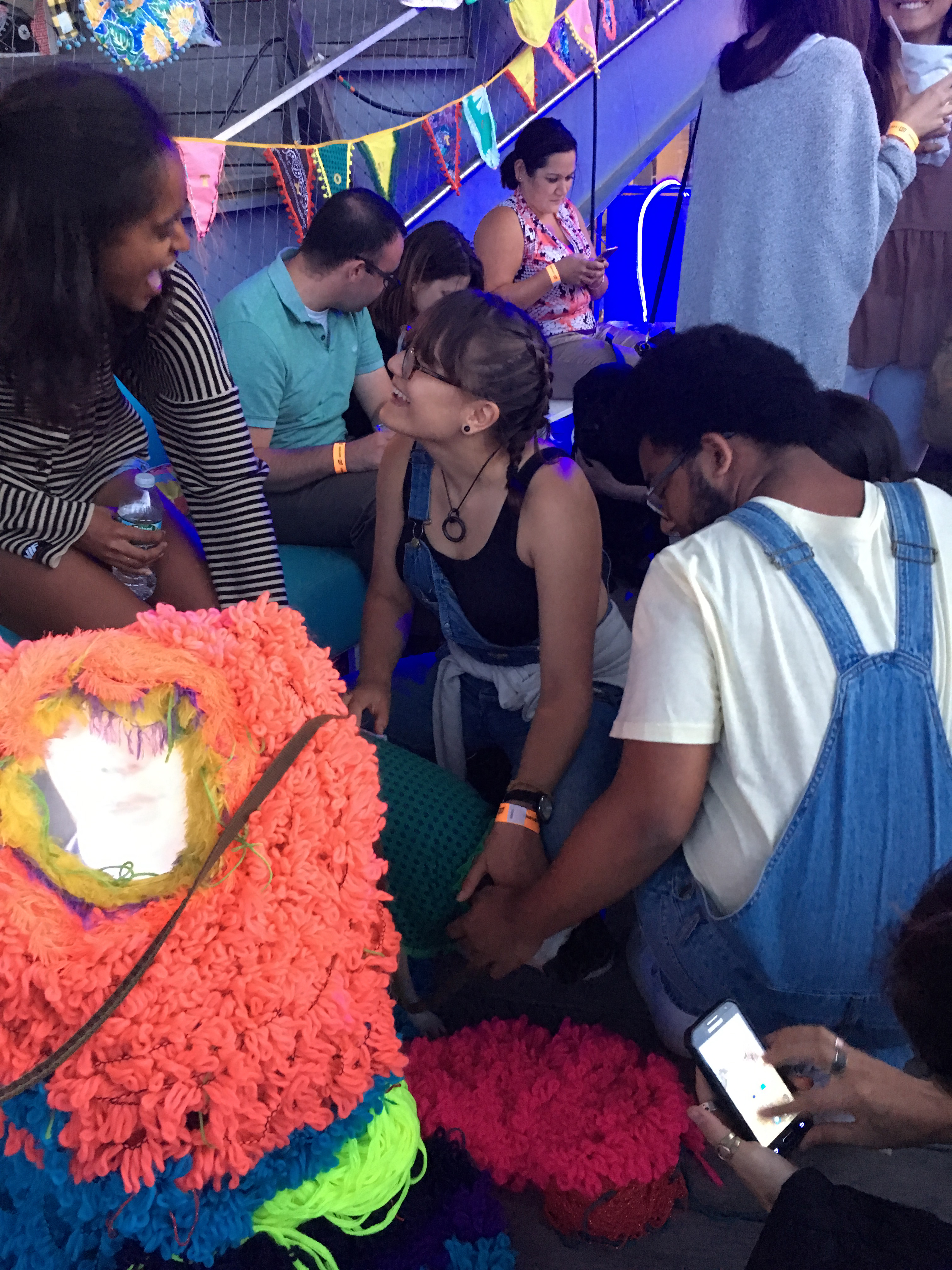 A group of individuals laugh as they pet dogs and look at art. 